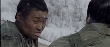 Movie still from “Tae Guk Gi: The Brotherhood of War” (2004), directed by Kang Je-kyu – A young man with his mouth wide open in the snow; Close Up shot, Over the shoulder angle