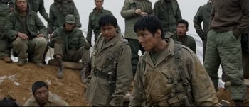 Movie still from “Tae Guk Gi: The Brotherhood of War” (2004), directed by Kang Je-kyu – A group of men standing next to each other on top of a hill; Medium shot, Over the shoulder angle