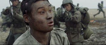 Movie still from “Tae Guk Gi: The Brotherhood of War” (2004), directed by Kang Je-kyu – Two soldiers in fatigues are standing in a field; Close Up shot, Over the shoulder angle