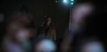 Movie still from “Altered Carbon” (2018), created by Laeta Kalogridis – A woman standing next to a chain link fence at night; Medium shot, Over the shoulder angle