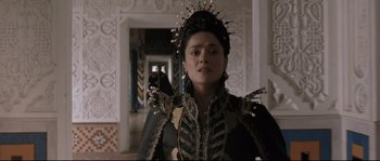 Movie still from “Tale of Tales” (2015), directed by Matteo Garrone – A woman in a black and gold dress with a bird on her head; Medium shot, Over the shoulder angle
