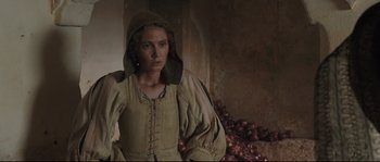 Movie still from “Tale of Tales” (2015), directed by Matteo Garrone – A woman in a medieval dress standing in front of a pile of red onions; Medium shot, Over the shoulder angle