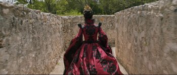 Movie still from “Tale of Tales” (2015), directed by Matteo Garrone – A woman in a red and black dress walking down a stone wall; Wide shot, High angle