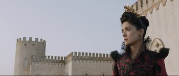 Movie still from “Tale of Tales” (2015), directed by Matteo Garrone – A woman in a red and black dress standing in front of a castle; Close Up shot, Low angle