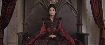 Movie still from “Tale of Tales” (2015), directed by Matteo Garrone – A woman sitting on top of a chair wearing a red and black dress; Medium shot, Overhead angle