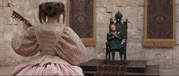 Movie still from “Tale of Tales” (2015), directed by Matteo Garrone – A doll sitting on top of a chair next to another doll; Wide shot, Over the shoulder angle
