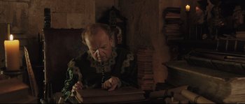 Movie still from “Tale of Tales” (2015), directed by Matteo Garrone – An older man is writing on a book; Medium shot, High angle