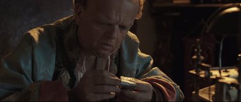 Movie still from “Tale of Tales” (2015), directed by Matteo Garrone – A man looking at a small object in his hands; Close Up shot, High angle
