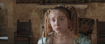 Movie still from “Tale of Tales” (2015), directed by Matteo Garrone – A young girl wearing a pearl necklace and a dress; Close Up shot, Over the shoulder angle