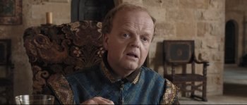 Movie still from “Tale of Tales” (2015), directed by Matteo Garrone – An older man in a blue and gold vest; Close Up shot, Over the shoulder angle