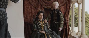 Movie still from “Tale of Tales” (2015), directed by Matteo Garrone – A woman sitting on a chair next to a man in a suit; Medium shot, High angle