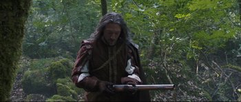 Movie still from “Tale of Tales” (2015), directed by Matteo Garrone – A man dressed in medieval clothing is holding a rifle; Medium shot, Over the shoulder angle