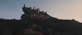 Movie still from “Tale of Tales” (2015), directed by Matteo Garrone – A castle on top of a hill with trees in the foreground; Extreme Wide shot, Low angle