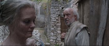 Movie still from “Tale of Tales” (2015), directed by Matteo Garrone – An older man and a younger woman standing next to each other in front of a stone building; Close Up shot, Over the shoulder angle