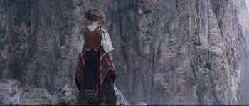 Movie still from “Tale of Tales” (2015), directed by Matteo Garrone – A woman dressed in medieval garb standing in front of a rock wall; Wide shot, Low angle