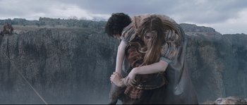 Movie still from “Tale of Tales” (2015), directed by Matteo Garrone – A woman holding a man on her back while standing next to a cliff; Wide shot, Low angle