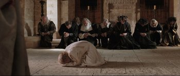 Movie still from “Tale of Tales” (2015), directed by Matteo Garrone – A man kneeling on the ground in front of a group of people; Wide shot, High angle