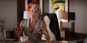 Movie still from “Ted Lasso” (2020), created by Brendan Hunt – A woman sitting at a table in front of a cup of coffee; Medium shot, Low angle
