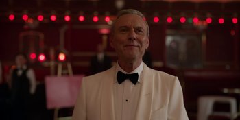Movie still from “Ted Lasso” (2020), created by Brendan Hunt – An older man wearing a white tuxedo and a bow tie; Close Up shot, Low angle