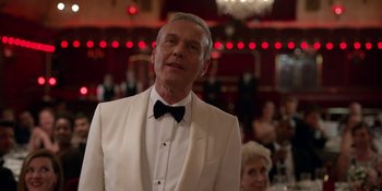 Movie still from “Ted Lasso” (2020), created by Brendan Hunt – An older man wearing a white tuxedo and a bow tie; Close Up shot, Over the shoulder angle