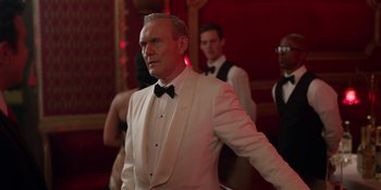 Movie still from “Ted Lasso” (2020), created by Brendan Hunt – An older man in a white suit and a black bow tie; Medium shot, Over the shoulder angle