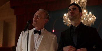 Movie still from “Ted Lasso” (2020), created by Brendan Hunt – A man in a white suit and a man in a black tie; Medium shot, Over the shoulder angle