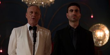 Movie still from “Ted Lasso” (2020), created by Brendan Hunt – A man and a man in a suit standing next to each other; Medium shot, Low angle