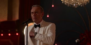 Movie still from “Ted Lasso” (2020), created by Brendan Hunt – A man in a white suit is holding a microphone; Close Up shot, Low angle