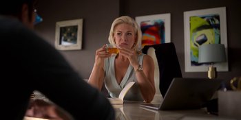 Movie still from “Ted Lasso” (2020), created by Brendan Hunt – A woman sitting at a table drinking a beverage; Medium shot, Over the shoulder angle
