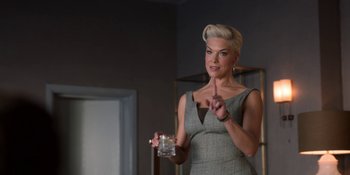Movie still from “Ted Lasso” (2020), created by Brendan Hunt – A woman in a dress holding a glass of water; Medium shot, Over the shoulder angle