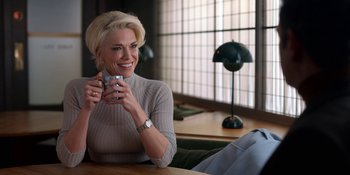Movie still from “Ted Lasso” (2020), created by Brendan Hunt – A woman sitting at a table holding a coffee mug; Medium shot, Over the shoulder angle