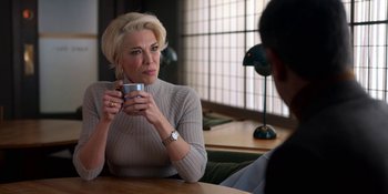 Movie still from “Ted Lasso” (2020), created by Brendan Hunt – A woman sitting at a table holding a coffee mug; Medium shot, Over the shoulder angle