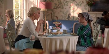 Movie still from “Ted Lasso” (2020), created by Brendan Hunt – A woman and a boy sitting at a table with a cake; Medium shot, Over the shoulder angle