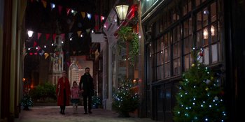 Movie still from “Ted Lasso” (2020), created by Brendan Hunt – A man , woman , and child walking down a street at night; Extreme Wide shot, High angle