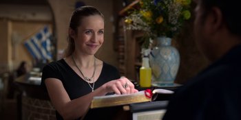 Movie still from “Ted Lasso” (2020), created by Brendan Hunt – A woman sitting in front of an open book at a desk; Close Up shot, Over the shoulder angle