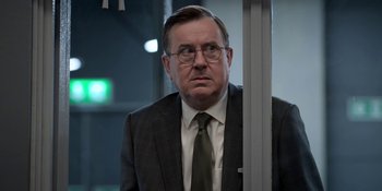 Movie still from “Ted Lasso” (2020), created by Brendan Hunt – A person wearing a suit and tie; Close Up shot, Over the shoulder angle