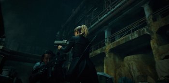 A woman in a black outfit holding a gun in her hand