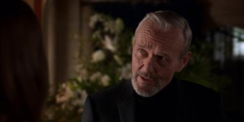 Movie still from “Ted Lasso” (2020), created by Brendan Hunt – An older man in a black suit and white beard; Close Up shot, Over the shoulder angle