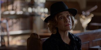 Movie still from “Ted Lasso” (2020), created by Brendan Hunt – A woman wearing a black hat sitting in a chair; Close Up shot, Over the shoulder angle