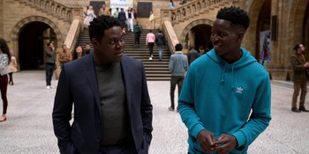 Movie still from “Ted Lasso” (2020), created by Brendan Hunt – Two young men are talking and laughing together; Medium shot, Over the shoulder angle
