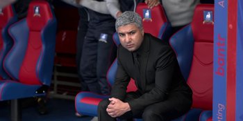 Movie still from “Ted Lasso” (2020), created by Brendan Hunt – A man in a suit sitting on a chair; Medium shot, High angle