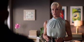 Movie still from “Ted Lasso” (2020), created by Brendan Hunt – A woman holding a glass of wine in a living room; Medium shot, Over the shoulder angle