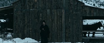 Movie still from “Terror on the Prairie” (2022), directed by Michael Polish – A person standing in front of a wooden wall; Wide shot, Low angle