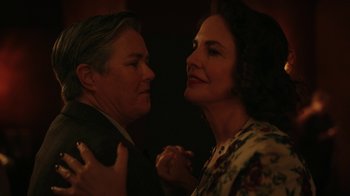 Movie still from “A League of Their Own” (2022), created by Abbi Jacobson – A man and a woman holding each other in a dark room; Close Up shot, Low angle