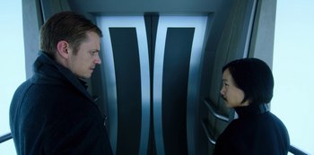 A man and a woman standing in front of each other in front of an elevator
