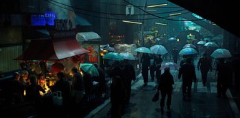 Movie still from “Altered Carbon” (2018), created by Laeta Kalogridis – A group of people walking down a street under umbrellas; Extreme Wide shot, High angle