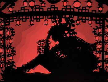 Movie still from “The Adventures of Prince Achmed” (1926), directed by Lotte Reiniger – A silhouette of a woman sitting on the ground with her legs crossed; Wide shot, Overhead angle