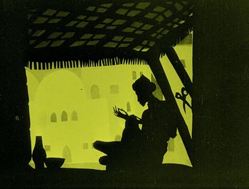 Movie still from “The Adventures of Prince Achmed” (1926), directed by Lotte Reiniger – A silhouette of a person sitting under an awning; Wide shot, Low angle