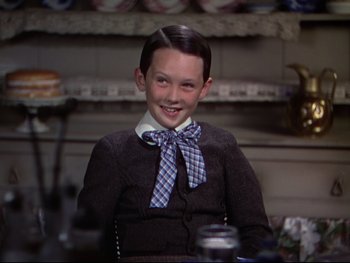 Movie still from “The Adventures of Tom Sawyer” (1938), directed by Norman Taurog – A young boy wearing a sweater and a bow tie; Medium shot, Over the shoulder angle