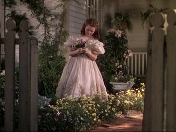 Movie still from “The Adventures of Tom Sawyer” (1938), directed by Norman Taurog – A girl in a pink dress holding a bouquet of flowers; Wide shot, High angle
